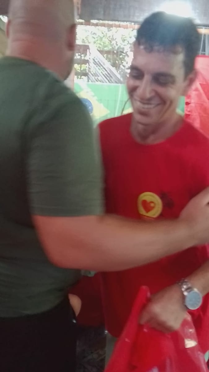Dois homens se cumprimentam sorrindo durante a montagem de um evento.