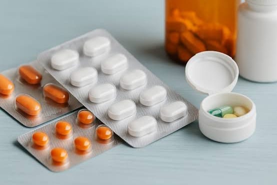 Cartelas de comprimidos e frascos de medicamento sobre uma mesa.