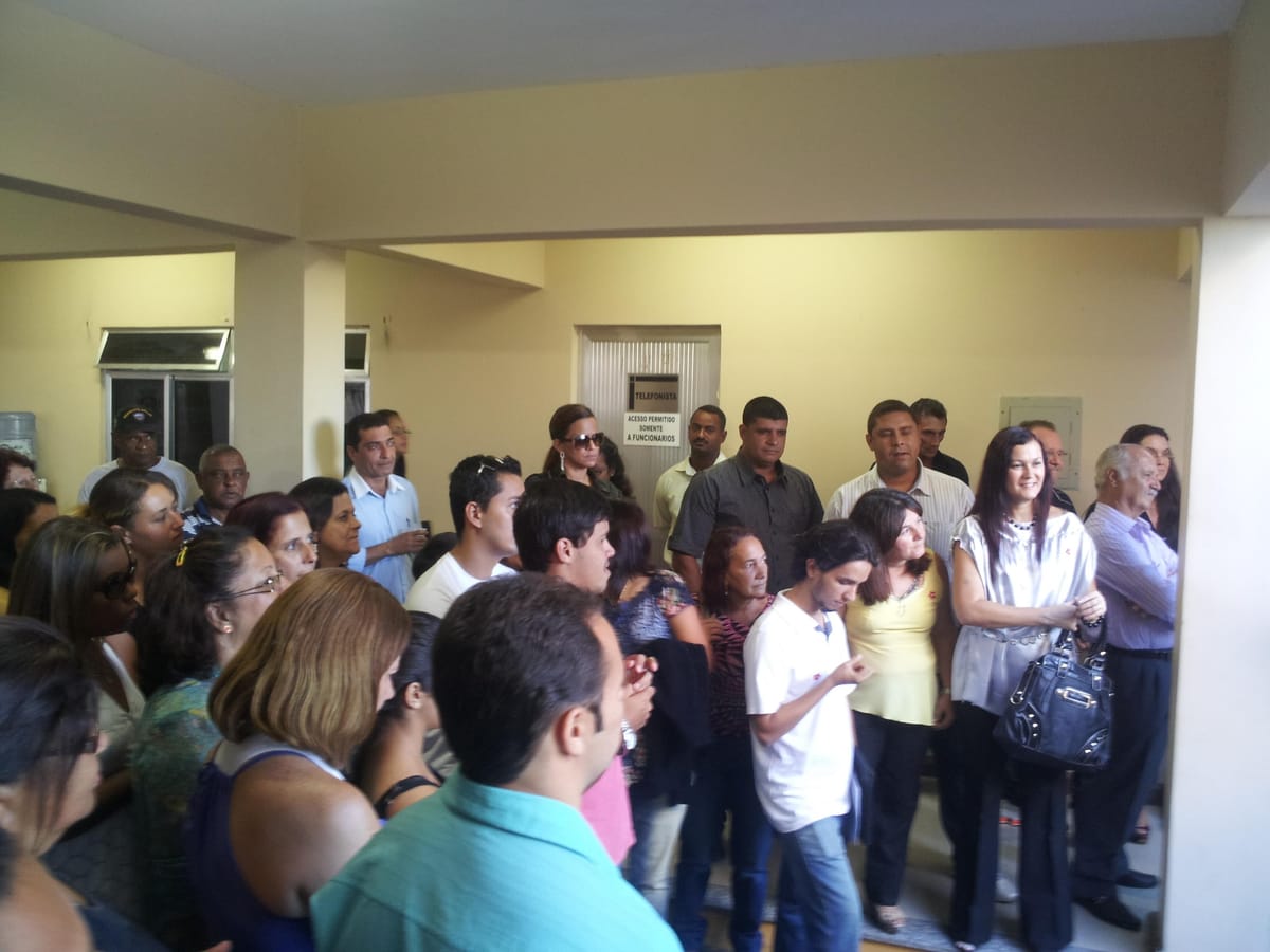 Grupo de adultos reunido no saguão de um prédio público durante uma inauguração.